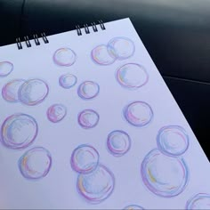 a drawing with colored pencils on paper next to a pen and some papers that have circles drawn on them