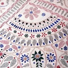 an embroidered tablecloth with flowers and leaves on it's edges, in red, white, blue and green colors