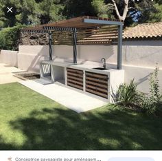 an outdoor kitchen is built into the side of a house with wood slats on it