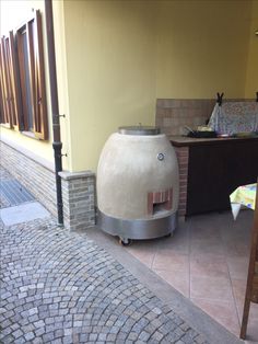 a large stone oven sitting on the side of a building next to a wooden table