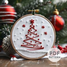 a cross stitch christmas tree ornament hanging from a hoop