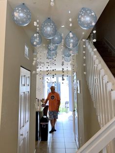 a man is walking down the hallway decorated with blue and white ornaments hanging from the ceiling