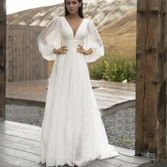 a woman in a white wedding dress standing on a wooden platform with her hands on her hips