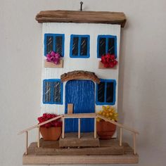 a doll house with blue windows and potted plants on the front porch is shown