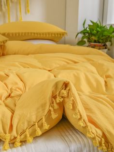 an unmade bed with yellow sheets and pillows