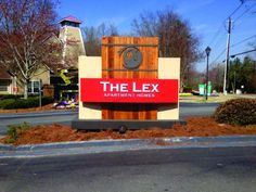 a sign for the flex apartment homes in front of a street with trees and bushes