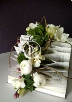 an open book with flowers on it sitting on a table