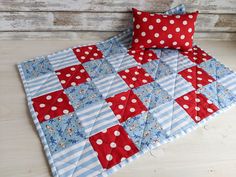 a red and blue quilted bed spread with polka dot pillows on top of it