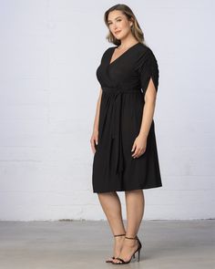 A signature wardrobe staple, the Eden Faux Wrap Dress features the illusion of a classic wrap.  A substantial faux tie belt accentuates your curves creating an elegant hourglass silhouette. The ruched hi-lo sleeves not only offer comfort but also add an unexpected update to this little black dress.  Effortlessly versatile, this plus size midi faux wrap dress easily transitions from the office to cocktail hour and even serves as a stylish option for wedding guest attire.  Designed Jumpsuit And Cardigan, Wedding Guest Attire, Chic Cardigan, Hourglass Silhouette, The Eden, Evening Gown Dresses, Guest Attire, Wedding Attire Guest, Black Tie Wedding