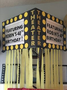 a birthday decoration with yellow streamers and black and white letters on it's sides