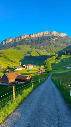 a rural road with houses and mountains in the background