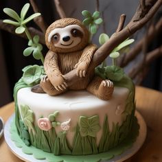 a cake decorated with a slotty sitting on top of a tree branch and leaves