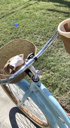 a blue bicycle with a basket on the handlebars parked next to a sidewalk