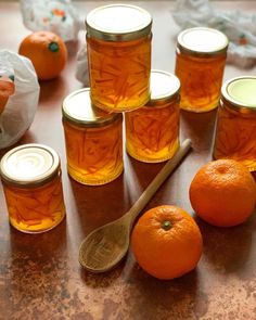 orange marmalade in glass jars with spoons on the table next to them