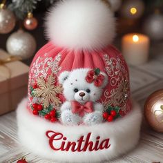 a white teddy bear wearing a red and white hat with the name gintha on it