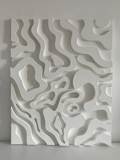 an abstract white sculpture is displayed on the wall