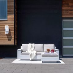 a white couch sitting on top of a brick floor next to a black wall and door