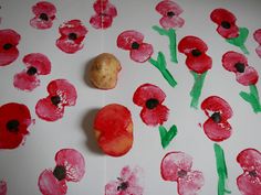 an apple and some red flowers on a white surface