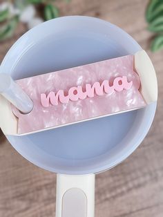 a pink object with the word moma on it sitting in a blue bowl next to a wooden table