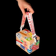 a hand is holding onto a box that has stickers on it