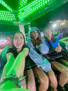 three girls are riding on a roller coaster at an amusement park in the night time