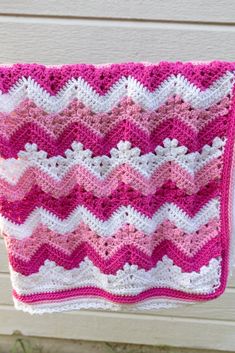 a pink and white crocheted blanket hanging from a clothes line