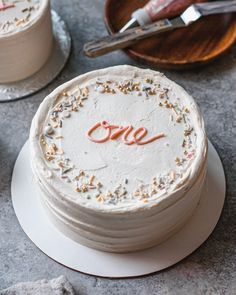 there is a cake with the word one on it and two other cakes in the background