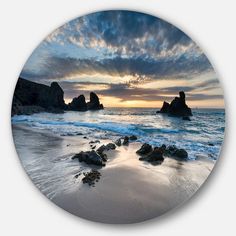 a beach with rocks and water under a cloudy sky