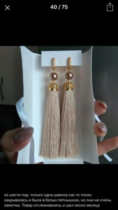 a pair of earrings with tassels and beads in a box on the table