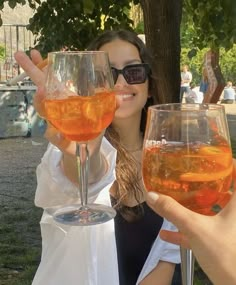 two women holding up wine glasses with orange liquid in them