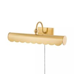 a gold wall light with a scalloped shade on the side and a white background