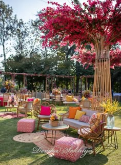 an outdoor seating area with pink flowers and wicker furniture on the grass in front of it