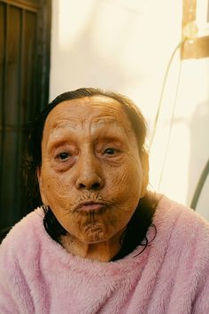 an old woman with wrinkles on her face and pink fur coat over her shoulders