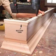 a man working on a piece of wood with a driller and tool box in front of him