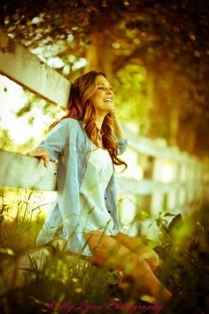 a woman is sitting on a fence and smiling