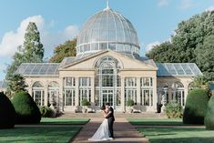 a bride and groom standing in front of a glass house