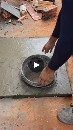 a person standing over a metal pan on top of cement