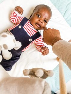 a baby is laying on the bed and being held up by someone's hand