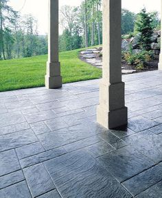 an empty patio with columns and grass in the background