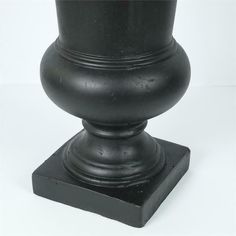 a black vase sitting on top of a wooden stand