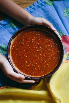 a person holding a bowl of chili on top of a towel