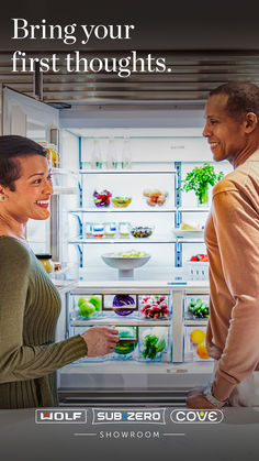 a man and woman standing in front of an open refrigerator with the door ajar