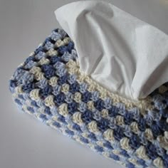 a blue and white crocheted blanket with a tissue