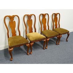 three antique chairs are lined up against the wall in a room with carpeted flooring