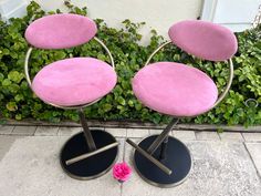 two pink chairs sitting on top of black bases