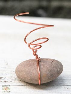 a wire wrapped around a rock sitting on top of a wooden table