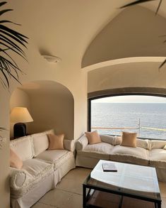 a living room filled with furniture and a large window overlooking the ocean in front of it