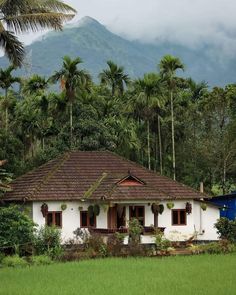 a white house in the middle of a lush green field with mountains in the background