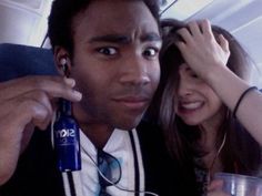 a man and woman sitting next to each other on an airplane with headphones in their ears