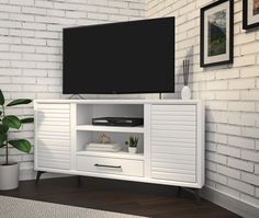 a flat screen tv sitting on top of a white entertainment center next to a potted plant